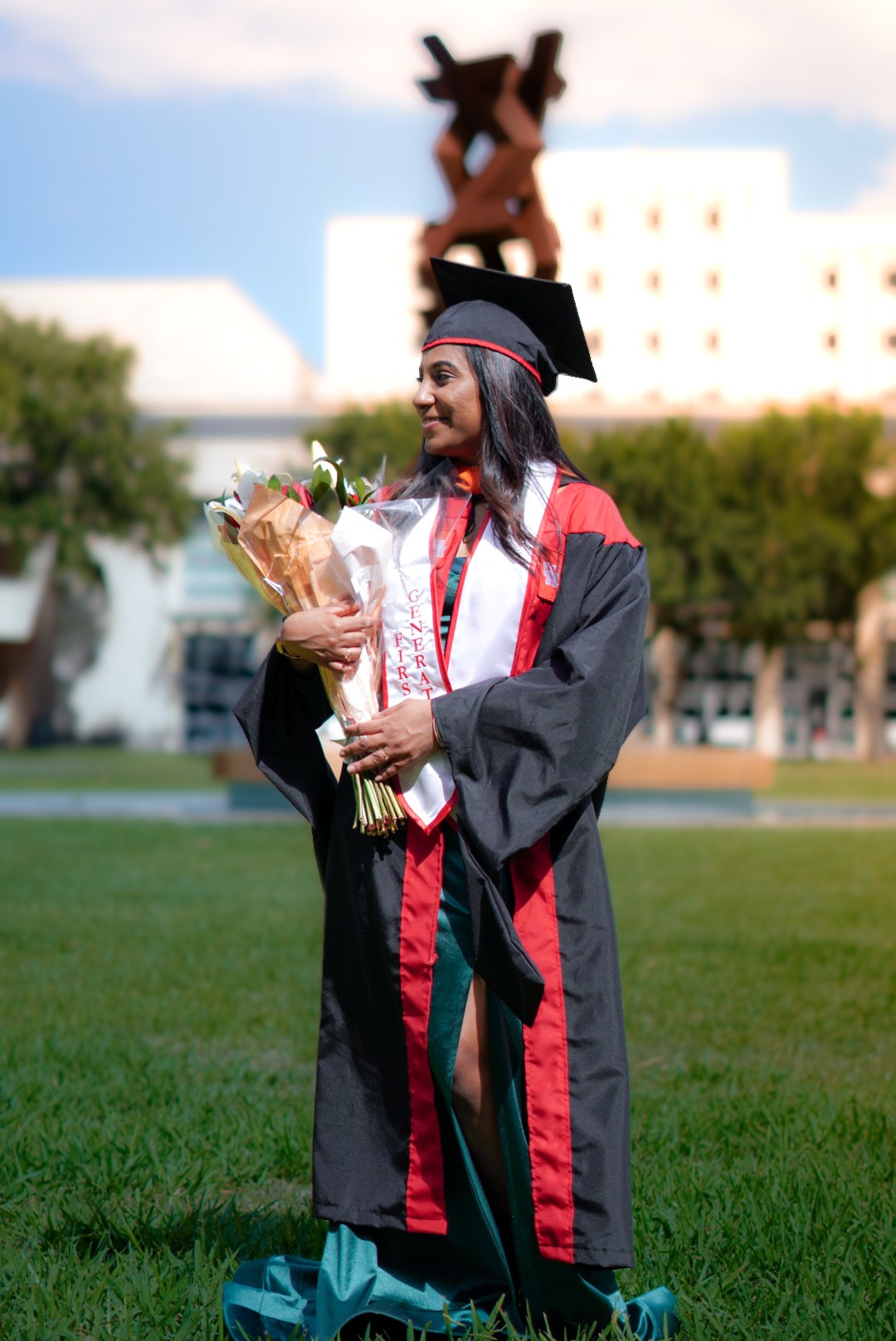 A graduate holding flowers on the campus lawn